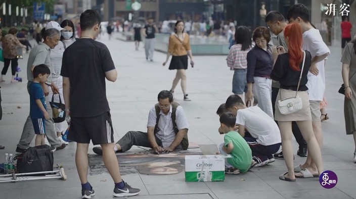 不時有市民圍觀,截肢街頭畫家畫畫。