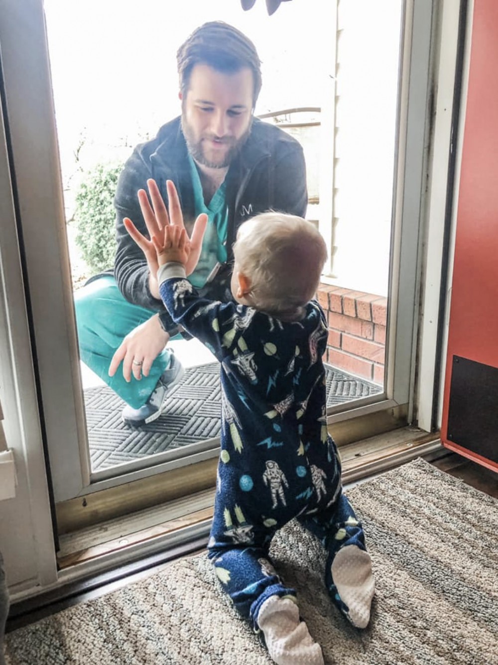 據外媒報導，相片中的男醫生賈里德·伯克斯（Jared Burks）來自阿肯色洲（state of Arkansas) ，他近來都站在前線工作對抗疫情，早前終獲休假回家，但因怕把痛毒傳染給家人，於是決定隔著玻璃與家人見面。