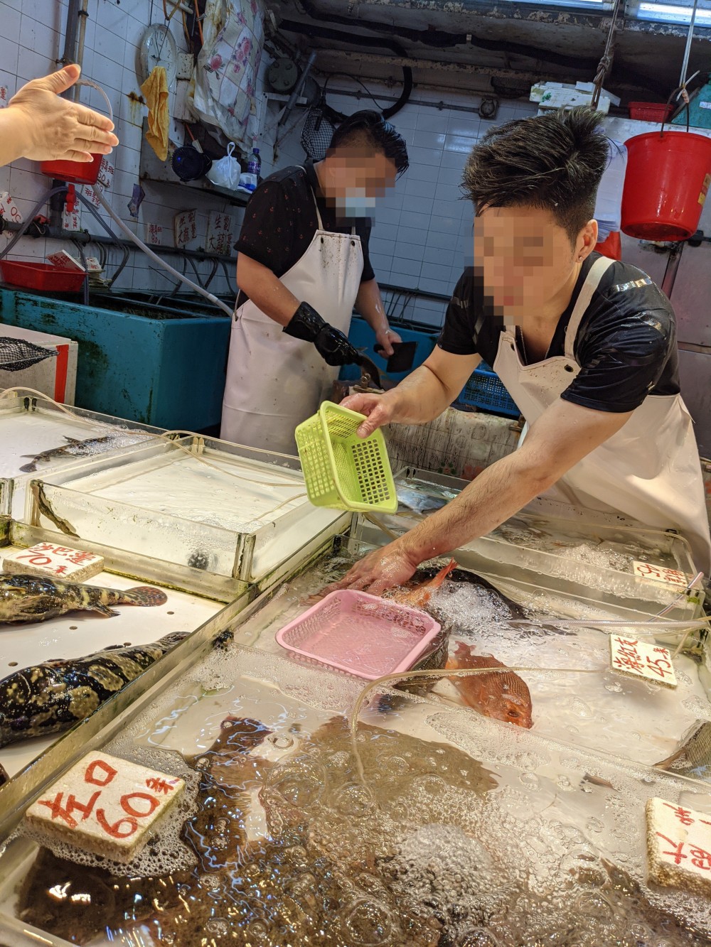  在青衣的一間街市，有攤販不戴口罩，為顧客揀魚。