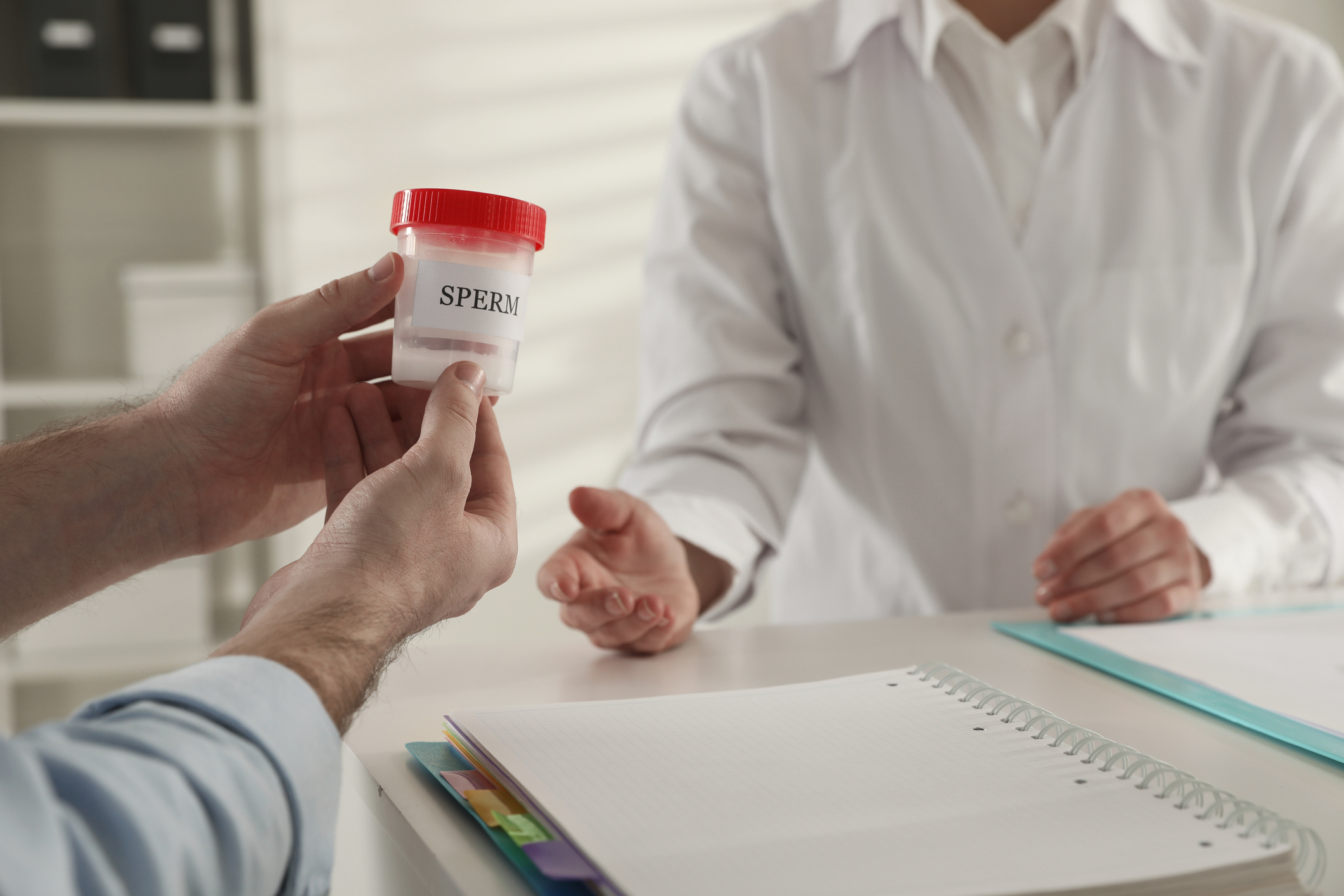 Donor giving container of sperm to doctor in hospital, closeup