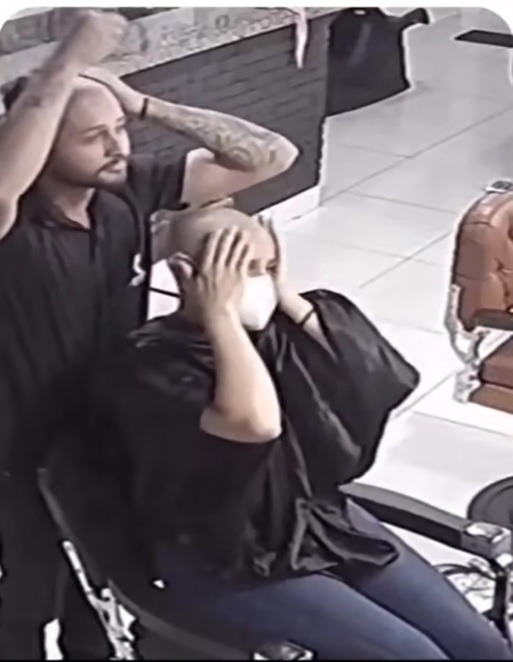 理髮師毫不猶豫地將自己的頭髮也剃光，女子難以置信地雙手抱頭。