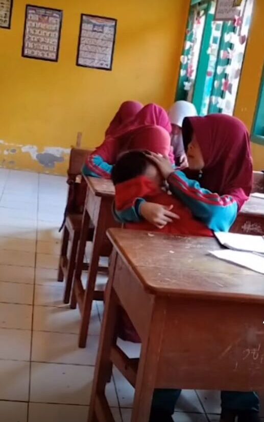 影片中見目前就讀2年級的9歲女童Nuraeni身穿校服,抱著2歲弟弟Akbar正在課室上課。